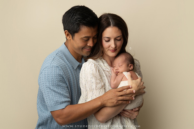Parents cuddling their newborn baby boy during a family portrait session at Studio 120 Photography.