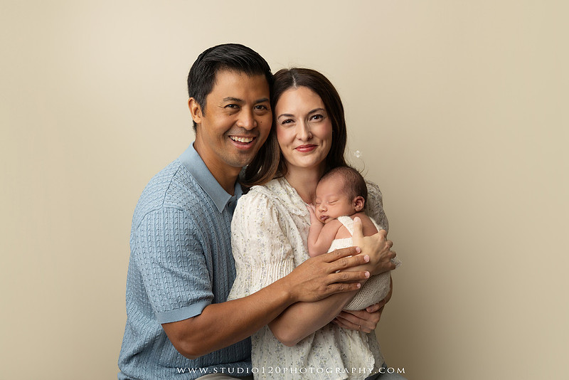 Parents cuddling their newborn baby boy during a family portrait session at Studio 120 Photography.