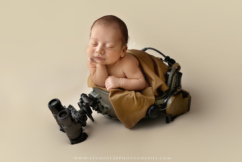 Big brother smiling beside his newborn baby brother during a sibling newborn photography session.