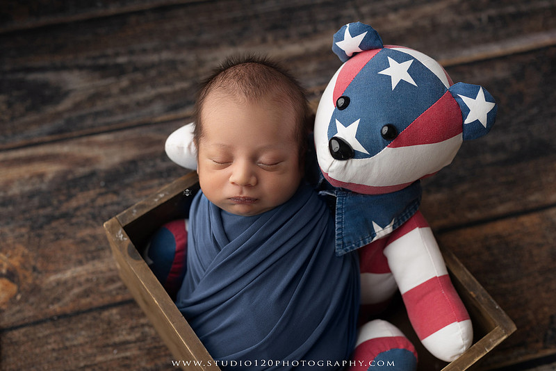 Big brother smiling beside his newborn baby brother during a sibling newborn photography session.