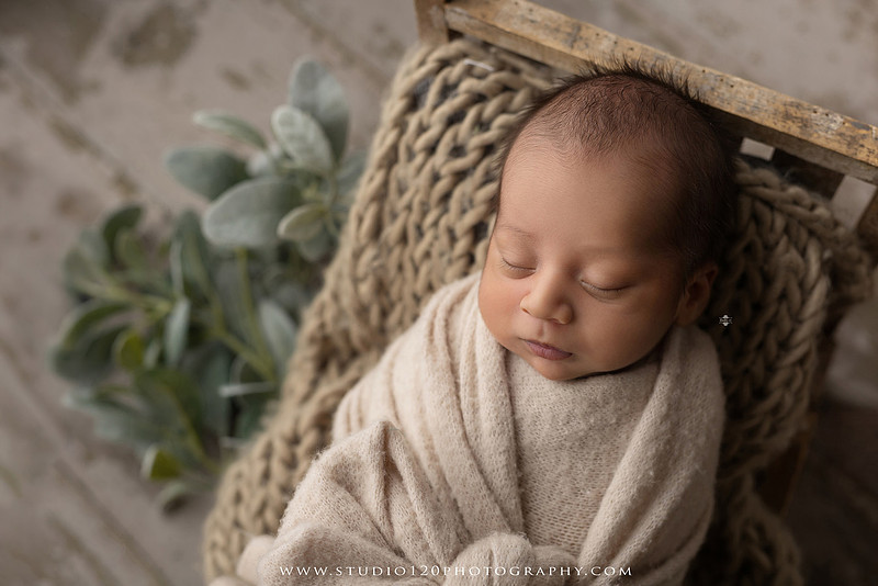 Big brother smiling beside his newborn baby brother during a sibling newborn photography session.