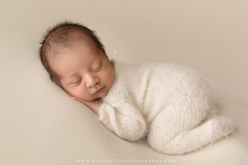 Big brother smiling beside his newborn baby brother during a sibling newborn photography session.
