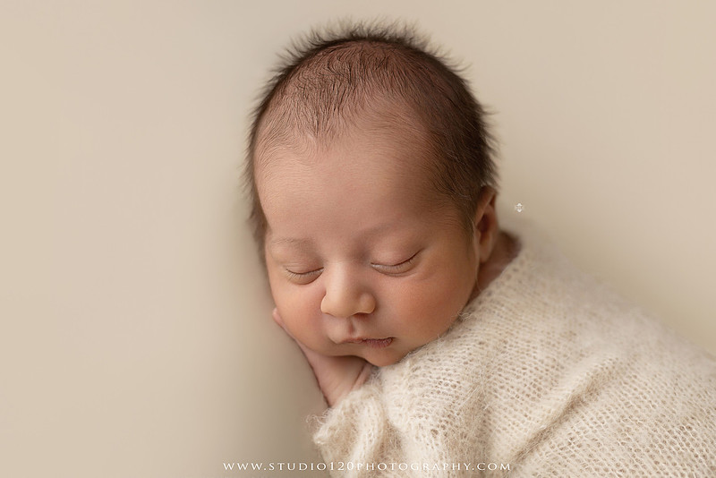 Big brother smiling beside his newborn baby brother during a sibling newborn photography session.