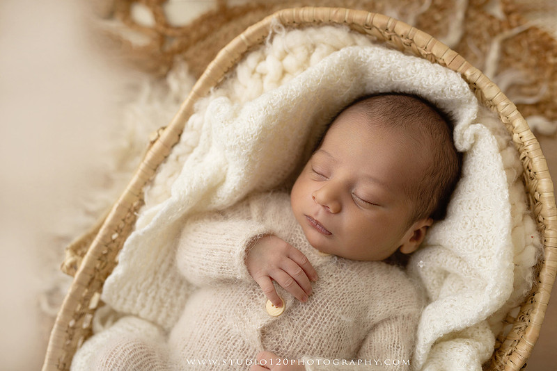 Big brother smiling beside his newborn baby brother during a sibling newborn photography session.