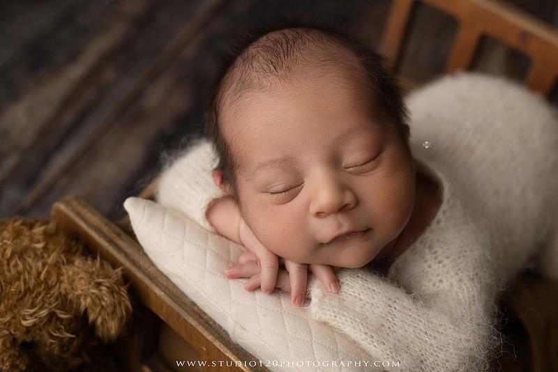 Big brother smiling beside his newborn baby brother during a sibling newborn photography session.
