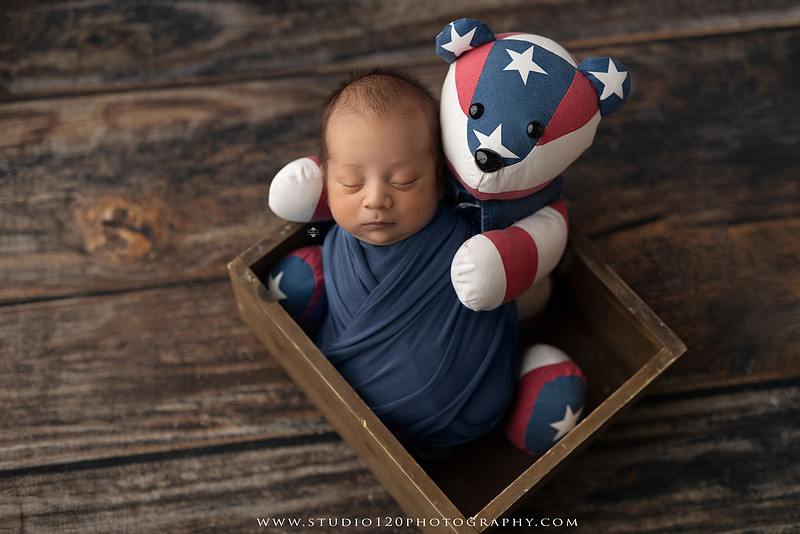 Big brother smiling beside his newborn baby brother during a sibling newborn photography session.