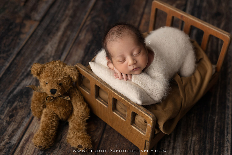 Big brother smiling beside his newborn baby brother during a sibling newborn photography session.