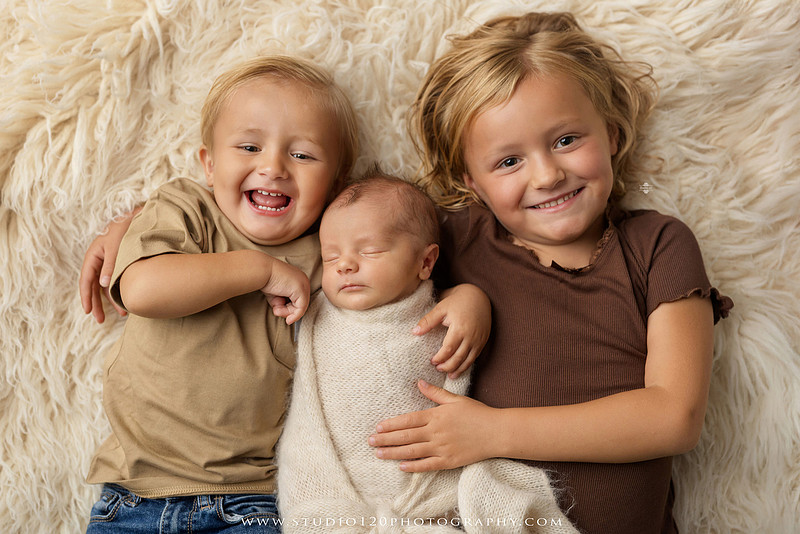 Professional newborn photography session in Ramona featuring a sleeping baby boy, sibling portraits, loving family photos, timeless neutral styling, wrapped newborn poses, and classic studio portraits by Studio 120 Photography.