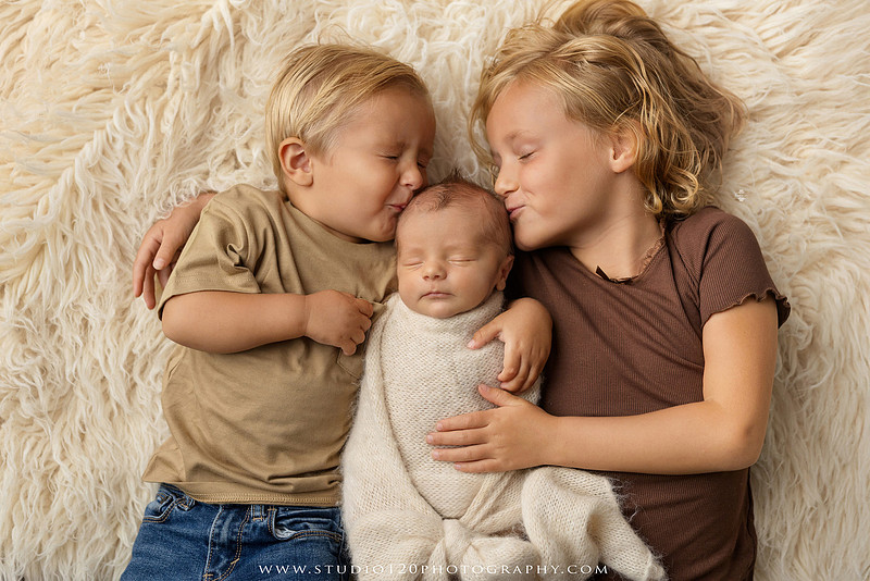 Professional newborn photography session in Ramona featuring a sleeping baby boy, sibling portraits, loving family photos, timeless neutral styling, wrapped newborn poses, and classic studio portraits by Studio 120 Photography.