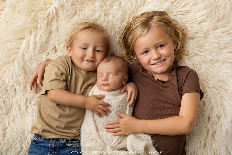 Professional newborn photography session in Ramona featuring a sleeping baby boy, sibling portraits, loving family photos, timeless neutral styling, wrapped newborn poses, and classic studio portraits by Studio 120 Photography.