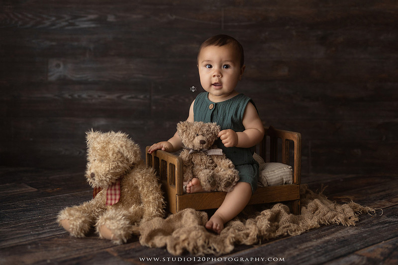 Baby boy sitter milestone portraits in Ramona photography studio featuring classic wooden toys, teddy bears, a vintage wooden bed, neutral props, natural textures, and timeless baby milestone photography capturing smiles, curiosity, and playful expressions.