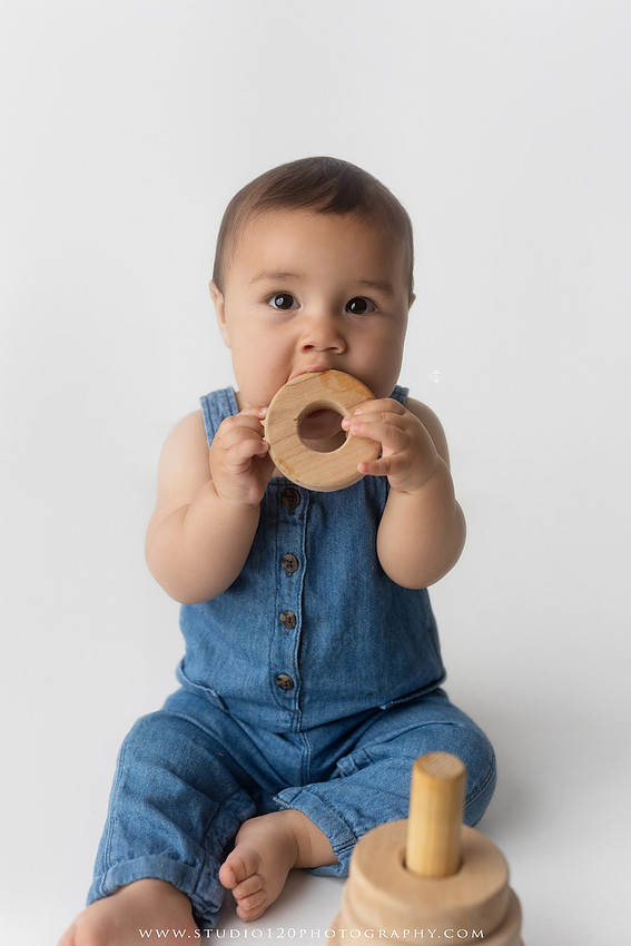 Baby boy sitter milestone portraits in Ramona photography studio featuring classic wooden toys, teddy bears, a vintage wooden bed, neutral props, natural textures, and timeless baby milestone photography capturing smiles, curiosity, and playful expressions.