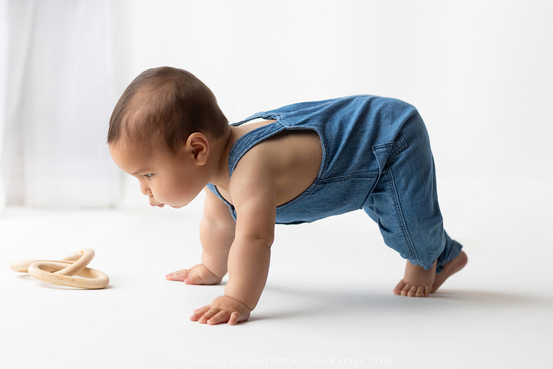 Baby boy sitter milestone portraits in Ramona photography studio featuring classic wooden toys, teddy bears, a vintage wooden bed, neutral props, natural textures, and timeless baby milestone photography capturing smiles, curiosity, and playful expressions.