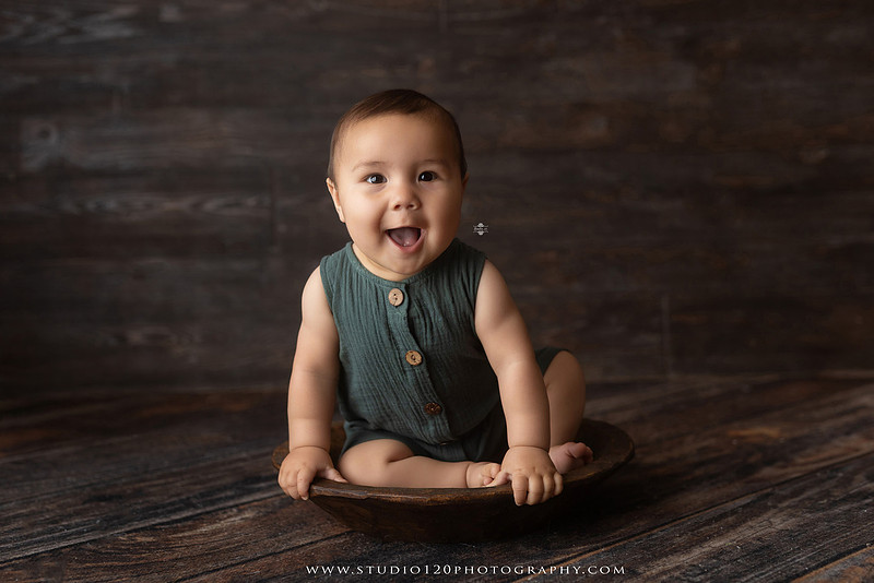 Baby boy sitter milestone portraits in Ramona photography studio featuring classic wooden toys, teddy bears, a vintage wooden bed, neutral props, natural textures, and timeless baby milestone photography capturing smiles, curiosity, and playful expressions.