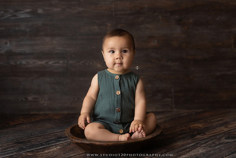 Baby boy sitter milestone portraits in Ramona photography studio featuring classic wooden toys, teddy bears, a vintage wooden bed, neutral props, natural textures, and timeless baby milestone photography capturing smiles, curiosity, and playful expressions.