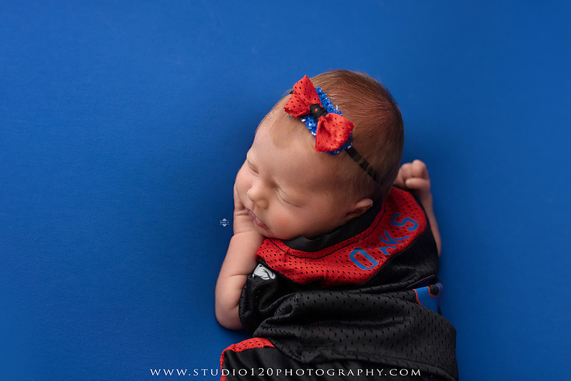 Professional newborn photography session featuring baby girl Astrid with custom Ramona Bulldogs football-themed portraits, a handcrafted Bulldogs newborn bucket wrap, football helmet and football, soft neutral newborn poses, vintage wooden bed with floral styling, plush bunny, blush and cream wraps, personalized 3D printed name sign, custom ASTRID letter artwork, and timeless studio newborn portraits by Studio 120 Photography in Ramona, CA.