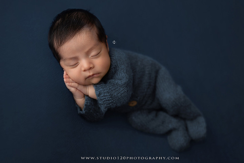 Newborn baby boy sleeping peacefully in neutral-toned wraps and rustic props, including a wooden bucket, teddy bear, and western-inspired cowboy outfit with denim overalls and a cowboy hat during a custom newborn photography session at Studio 120 Photography in Ramona, California.