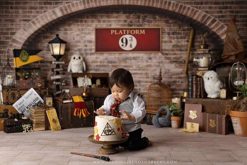 One-year-old boy dressed as a wizard smiling beside a Harry Potter-inspired birthday cake during a magical first birthday cake smash in San Diego.