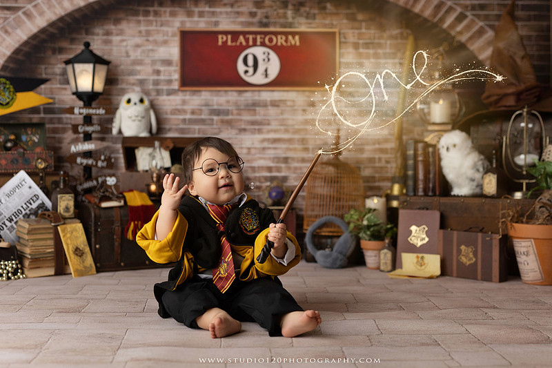 One-year-old boy dressed as a wizard smiling beside a Harry Potter-inspired birthday cake during a magical first birthday cake smash in San Diego.