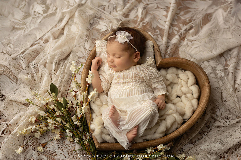 A collection of professional newborn portraits featuring a sleeping baby girl photographed in soft blush pink, ivory, and warm neutral tones. The gallery includes delicate floral headbands, a layered pink tutu, cozy cream wraps, a knitted lamb bonnet in a rustic wooden bucket, and beautiful cherry blossom accents. Images showcase a variety of classic newborn poses on textured blankets, nestled in a floral basket, and wrapped in timeless knit fabrics. Captured at Studio 120 Photography in Ramona, serving San Diego families with fine art newborn photography.