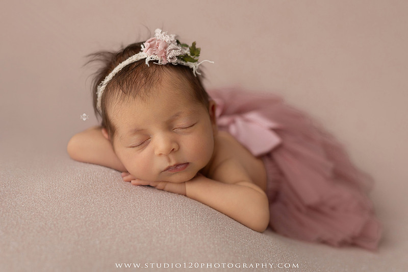 A collection of professional newborn portraits featuring a sleeping baby girl photographed in soft blush pink, ivory, and warm neutral tones. The gallery includes delicate floral headbands, a layered pink tutu, cozy cream wraps, a knitted lamb bonnet in a rustic wooden bucket, and beautiful cherry blossom accents. Images showcase a variety of classic newborn poses on textured blankets, nestled in a floral basket, and wrapped in timeless knit fabrics. Captured at Studio 120 Photography in Ramona, serving San Diego families with fine art newborn photography.