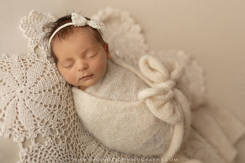 A collection of professional newborn portraits featuring a sleeping baby girl photographed in soft blush pink, ivory, and warm neutral tones. The gallery includes delicate floral headbands, a layered pink tutu, cozy cream wraps, a knitted lamb bonnet in a rustic wooden bucket, and beautiful cherry blossom accents. Images showcase a variety of classic newborn poses on textured blankets, nestled in a floral basket, and wrapped in timeless knit fabrics. Captured at Studio 120 Photography in Ramona, serving San Diego families with fine art newborn photography.