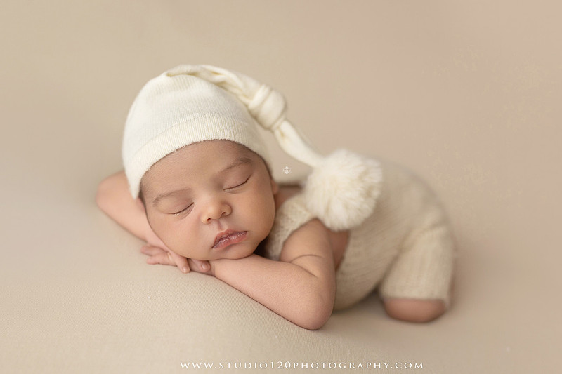 A professional newborn photography gallery featuring baby Caleb with his family at Studio 120 Photography in Ramona. The collection includes timeless family portraits with parents and four siblings, heartfelt individual parent and baby portraits, sibling photos gathered around a miniature crib, classic wrapped newborn poses, a personalized knit nightcap embroidered with Caleb's name, a custom football-themed newborn setup on a football under stadium lights, a football bowl prop with vintage football décor, and an organic newborn portrait with rich green knit textures and natural greenery. Soft neutral tones, personalized details, and family-centered images celebrate the arrival of a new baby while serving families throughout Ramona and the San Diego area.