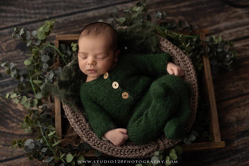 A professional newborn photography gallery featuring baby Caleb with his family at Studio 120 Photography in Ramona. The collection includes timeless family portraits with parents and four siblings, heartfelt individual parent and baby portraits, sibling photos gathered around a miniature crib, classic wrapped newborn poses, a personalized knit nightcap embroidered with Caleb's name, a custom football-themed newborn setup on a football under stadium lights, a football bowl prop with vintage football décor, and an organic newborn portrait with rich green knit textures and natural greenery. Soft neutral tones, personalized details, and family-centered images celebrate the arrival of a new baby while serving families throughout Ramona and the San Diego area.