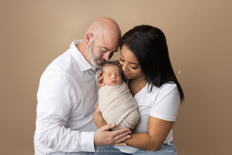 A professional newborn photography gallery featuring baby Caleb with his family at Studio 120 Photography in Ramona. The collection includes timeless family portraits with parents and four siblings, heartfelt individual parent and baby portraits, sibling photos gathered around a miniature crib, classic wrapped newborn poses, a personalized knit nightcap embroidered with Caleb's name, a custom football-themed newborn setup on a football under stadium lights, a football bowl prop with vintage football décor, and an organic newborn portrait with rich green knit textures and natural greenery. Soft neutral tones, personalized details, and family-centered images celebrate the arrival of a new baby while serving families throughout Ramona and the San Diego area.