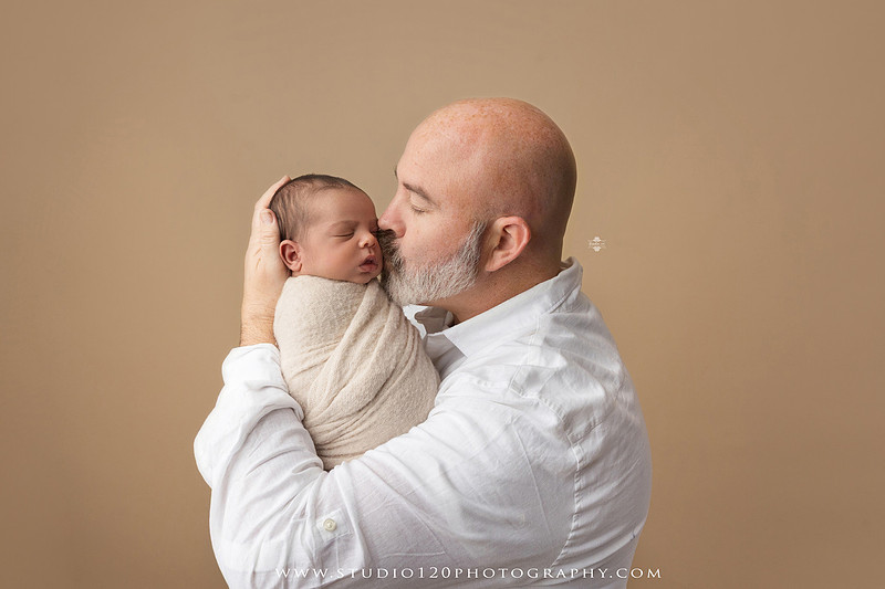 A professional newborn photography gallery featuring baby Caleb with his family at Studio 120 Photography in Ramona. The collection includes timeless family portraits with parents and four siblings, heartfelt individual parent and baby portraits, sibling photos gathered around a miniature crib, classic wrapped newborn poses, a personalized knit nightcap embroidered with Caleb's name, a custom football-themed newborn setup on a football under stadium lights, a football bowl prop with vintage football décor, and an organic newborn portrait with rich green knit textures and natural greenery. Soft neutral tones, personalized details, and family-centered images celebrate the arrival of a new baby while serving families throughout Ramona and the San Diego area.