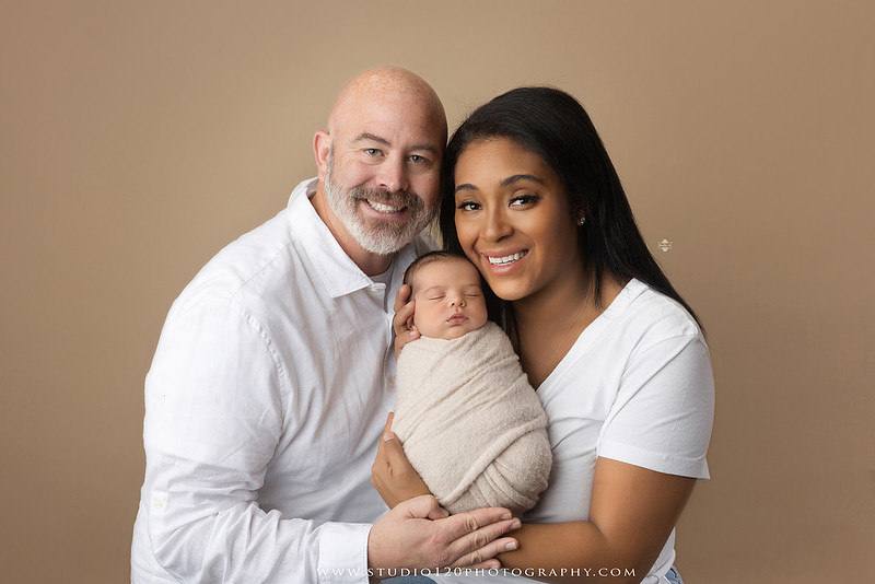 A professional newborn photography gallery featuring baby Caleb with his family at Studio 120 Photography in Ramona. The collection includes timeless family portraits with parents and four siblings, heartfelt individual parent and baby portraits, sibling photos gathered around a miniature crib, classic wrapped newborn poses, a personalized knit nightcap embroidered with Caleb's name, a custom football-themed newborn setup on a football under stadium lights, a football bowl prop with vintage football décor, and an organic newborn portrait with rich green knit textures and natural greenery. Soft neutral tones, personalized details, and family-centered images celebrate the arrival of a new baby while serving families throughout Ramona and the San Diego area.
