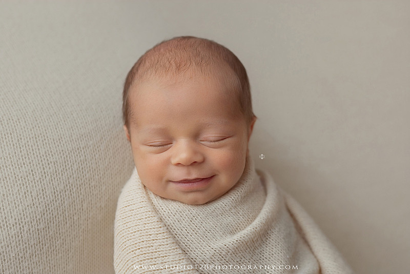 A collection of timeless newborn portraits featuring a sleeping baby boy photographed in Studio 120 Photography's Ramona studio. The gallery includes organic, neutral styling with soft cream wraps, textured knit blankets, rustic wooden bowls, vintage wash tubs, woven baskets, a modern macramé hammock, and a miniature woodland chair surrounded by handcrafted pine trees. Rich wood tones, eucalyptus greenery, dried botanicals, and warm natural textures create an elegant, earthy aesthetic. The collection also features simple beanbag portraits highlighting the baby's tiny features, peaceful sleeping poses, sweet smiles, and bright awake expressions. These fine art newborn photographs capture the beauty of a baby's earliest days with classic, heirloom-quality styling for families throughout Ramona, San Diego, Poway, Escondido, Lakeside, El Cajon, and surrounding Southern California communities.
