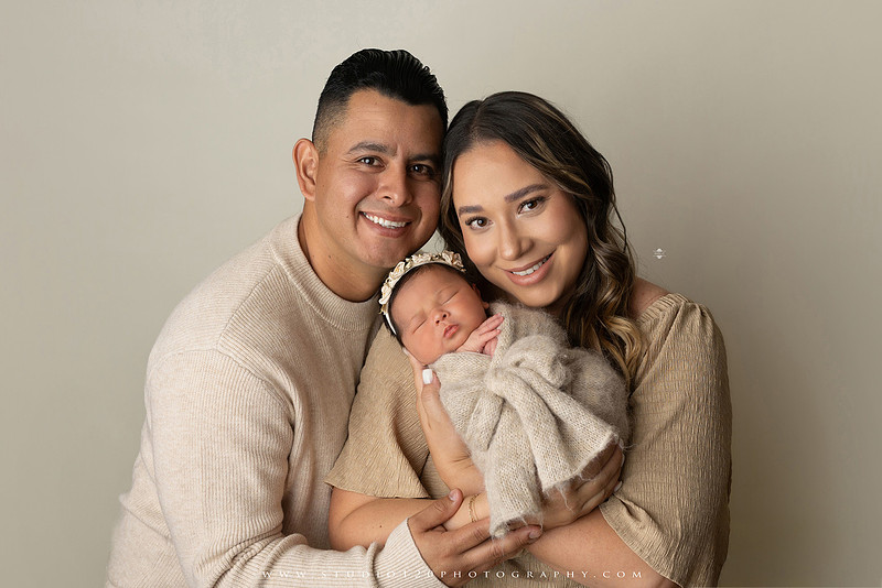 Timeless family newborn portraits featuring parents, siblings, and their new baby girl in soft neutral tones. The gallery includes standing family portraits, overhead sibling and newborn portraits, and natural moments celebrating the love, connection, and joy of welcoming a new baby. Captured at Studio 120 Photography in Ramona, serving San Diego County.