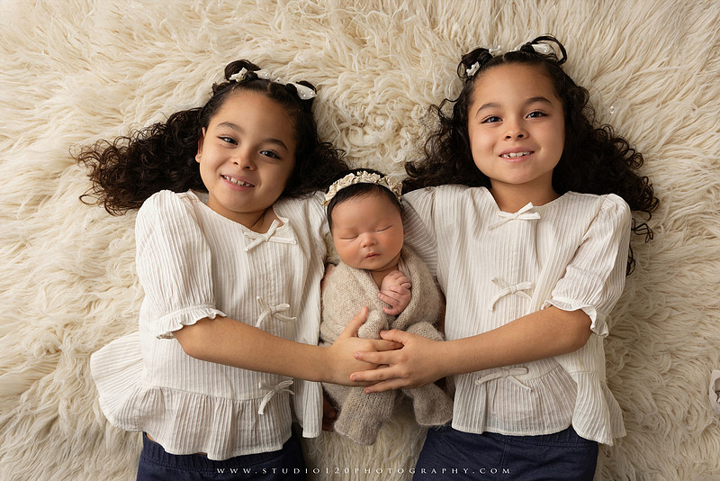 Timeless family newborn portraits featuring parents, siblings, and their new baby girl in soft neutral tones. The gallery includes standing family portraits, overhead sibling and newborn portraits, and natural moments celebrating the love, connection, and joy of welcoming a new baby. Captured at Studio 120 Photography in Ramona, serving San Diego County.