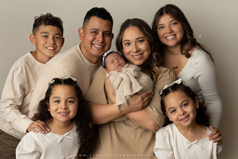 Timeless family newborn portraits featuring parents, siblings, and their new baby girl in soft neutral tones. The gallery includes standing family portraits, overhead sibling and newborn portraits, and natural moments celebrating the love, connection, and joy of welcoming a new baby. Captured at Studio 120 Photography in Ramona, serving San Diego County.