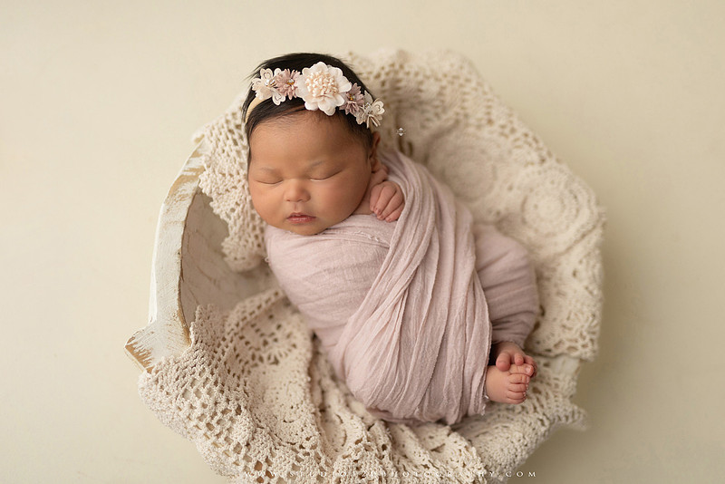 A collection of newborn baby girl portraits featuring peaceful sleeping poses, soft neutral wraps, delicate floral headbands, textured blankets, rustic baskets, natural wood props, creamy backdrops, and a special police tribute setup with a badge and Thin Blue Line flag. The gallery showcases timeless, baby-led newborn photography with warm, organic tones at Studio 120 Photography in Ramona, serving San Diego County.
